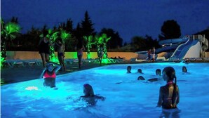 A swimming pool area with water slides and palm trees. - Mobile home in camping Le mas de l'isle (LUNEL)