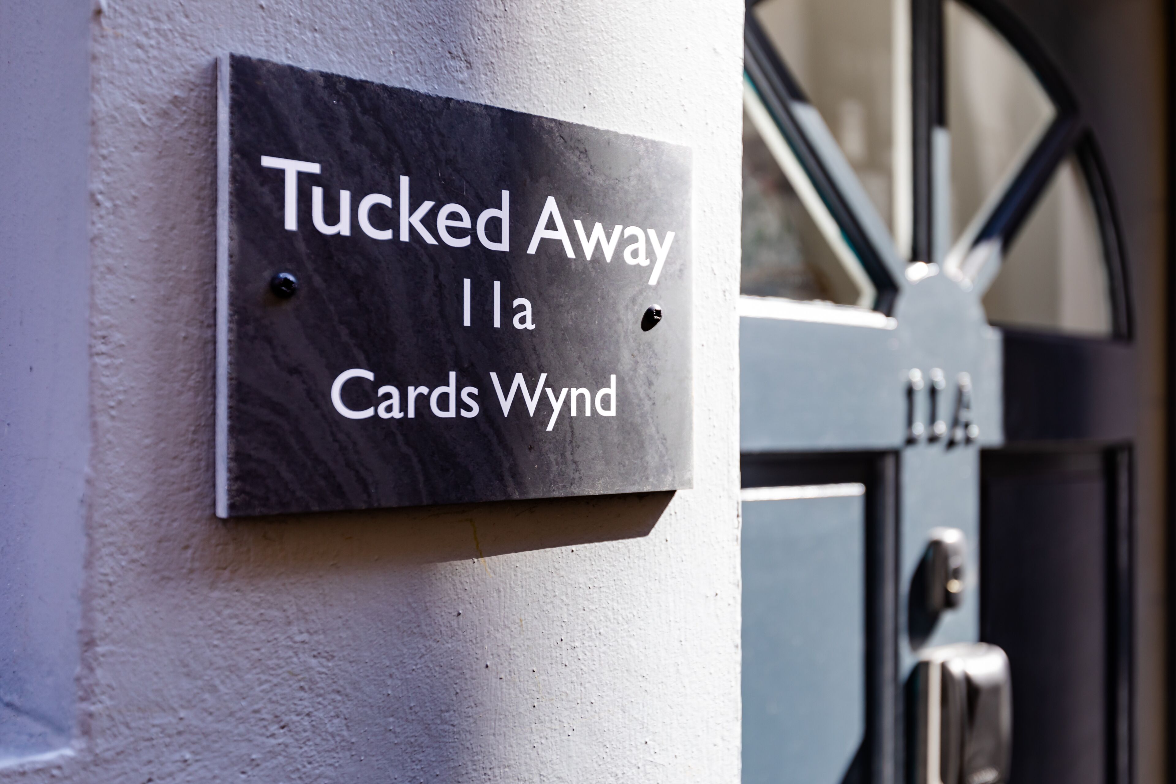 A sign with the text "Tucked Away" and "Cardas Wyn" on a building facade.