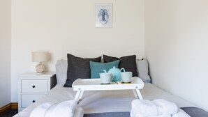 A neatly made bed with a tray holding two cups and a teapot, a bedside lamp, and a framed picture on the wall. - Shorefront Anstruther Home - 2 Bedrooms (Anstruther)
