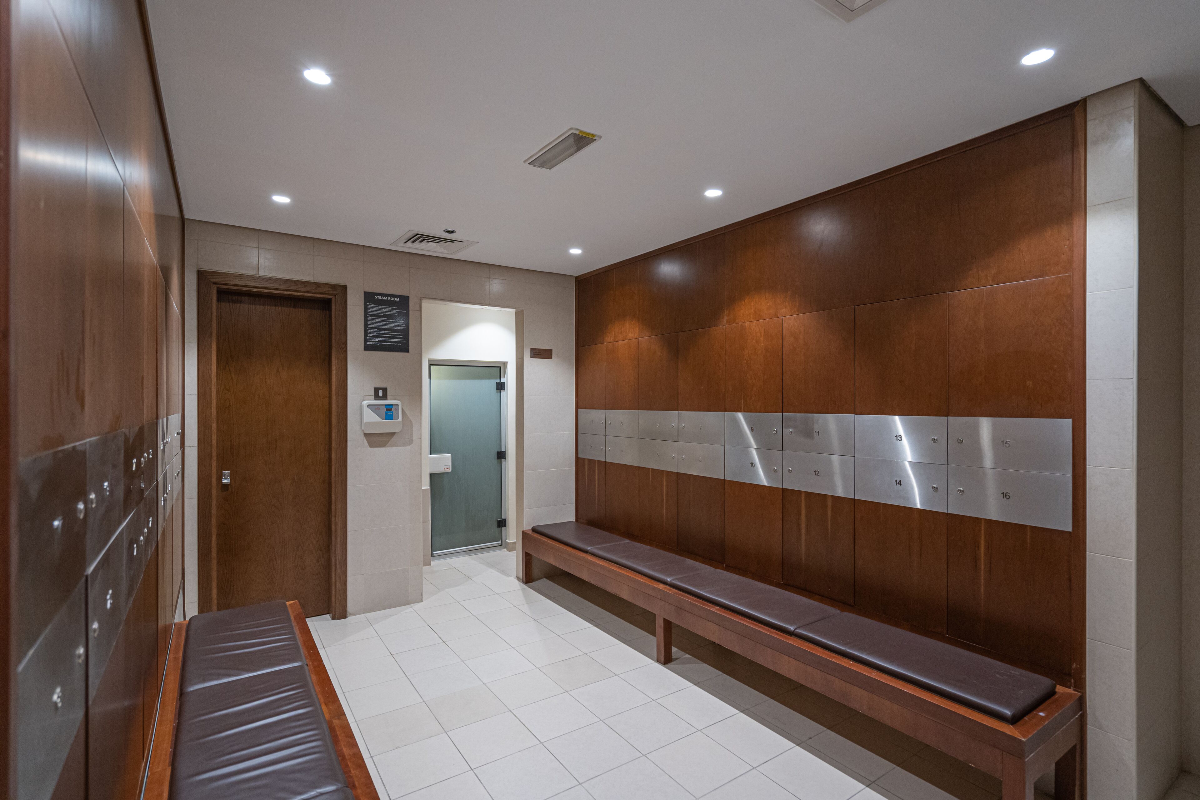 Een moderne wachtruimte met een bank, houten wandbekleding, een vastgeplakte kleedkamer en een betegelde vloer.