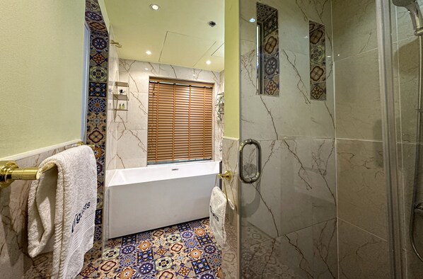 A bathroom with a bathtub, a shower, and a tiled floor.