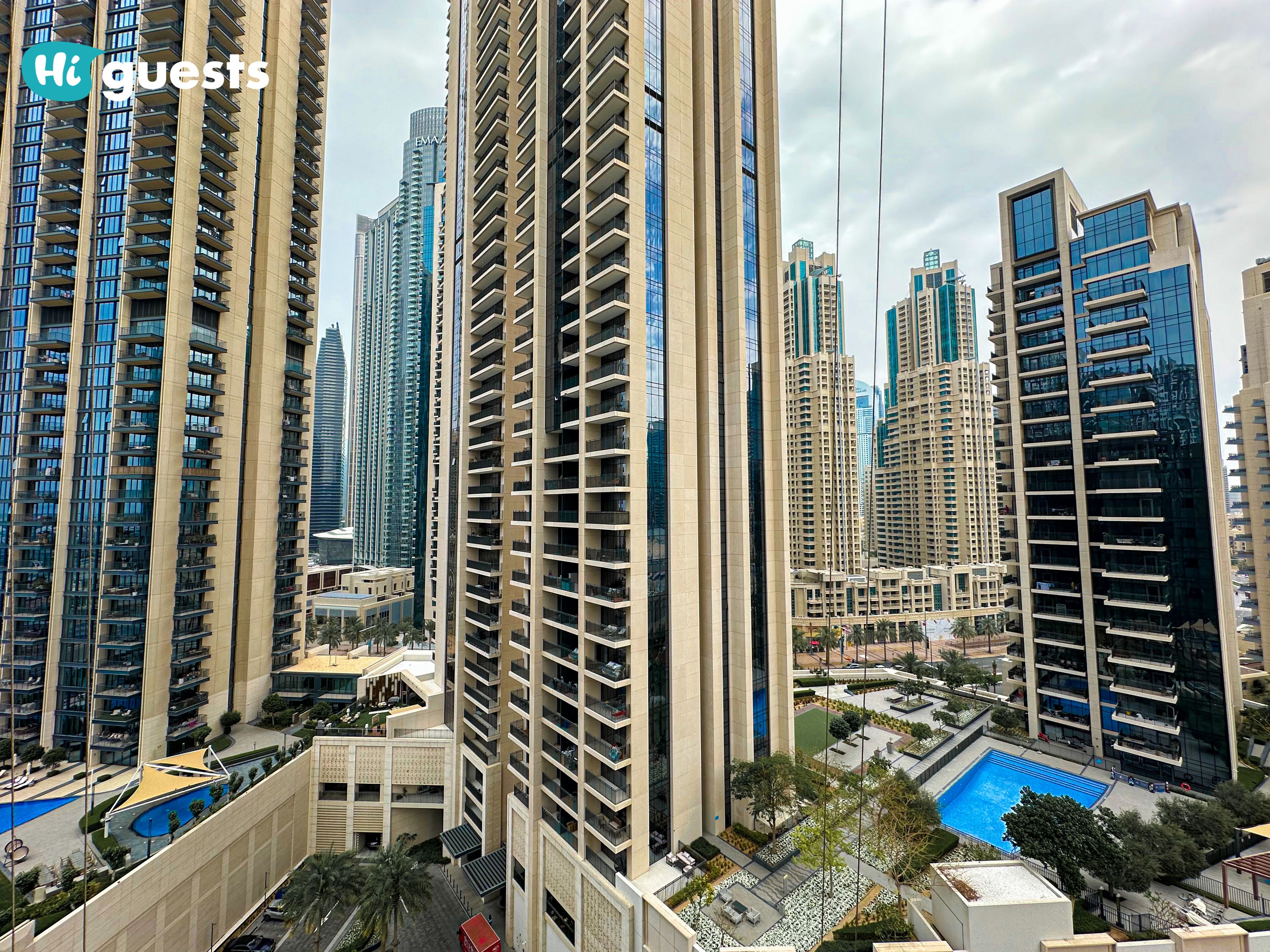 A high-rise residential building with multiple balconies, a rooftop pool, and surrounding modern architecture.