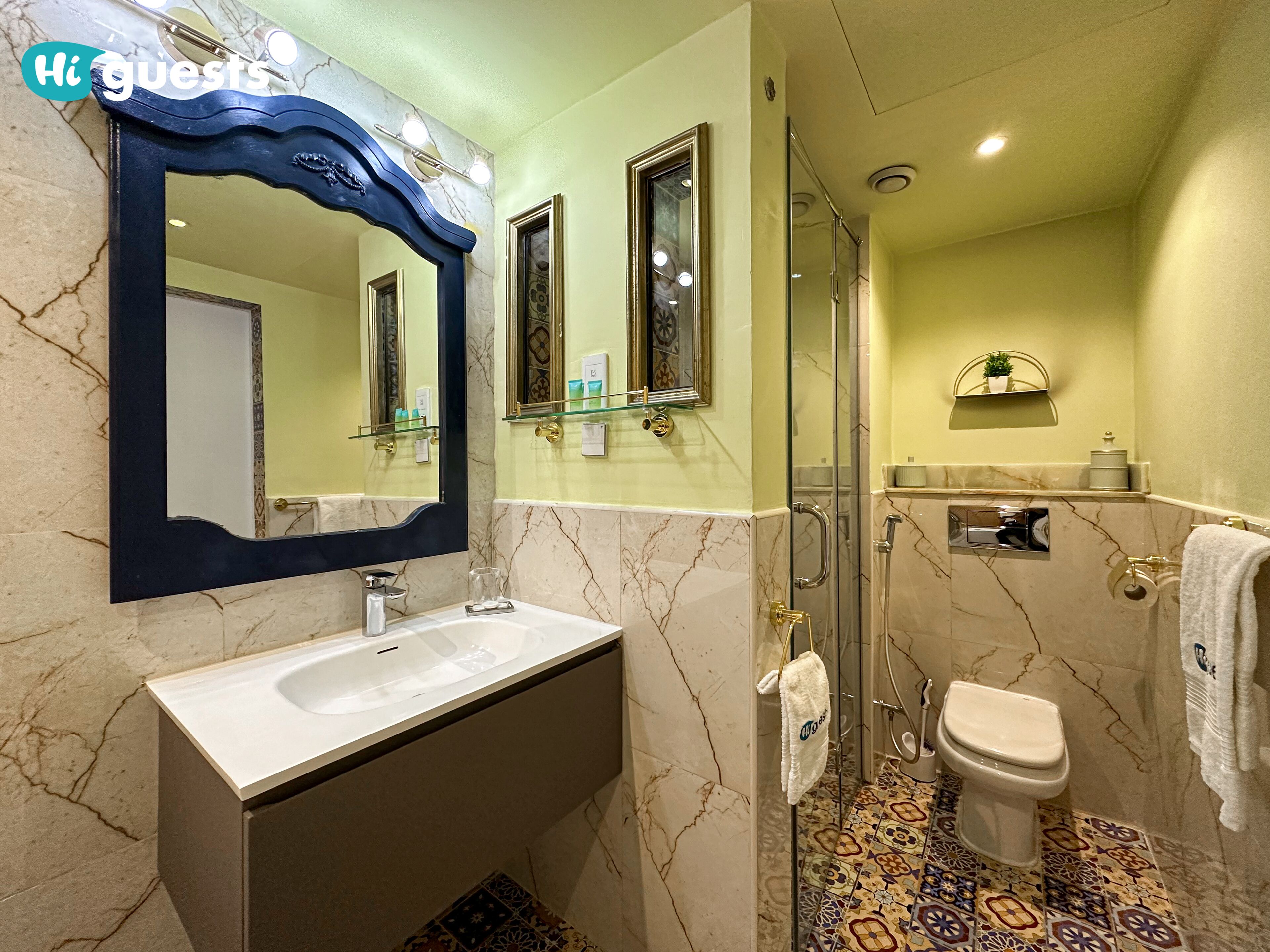 Une salle de bain avec un lavabo en marbre, un grand miroir, une cabine de douche en verre et des toilettes.
