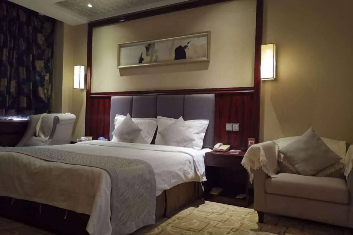 Ein Hotelzimmer mit einem großen Bett, Nachttischen, einer Sitzecke und einem Gemälde an der Wand.