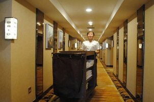 A hotel hallway with a reception desk, framed pictures on the walls, and a carpeted floor.