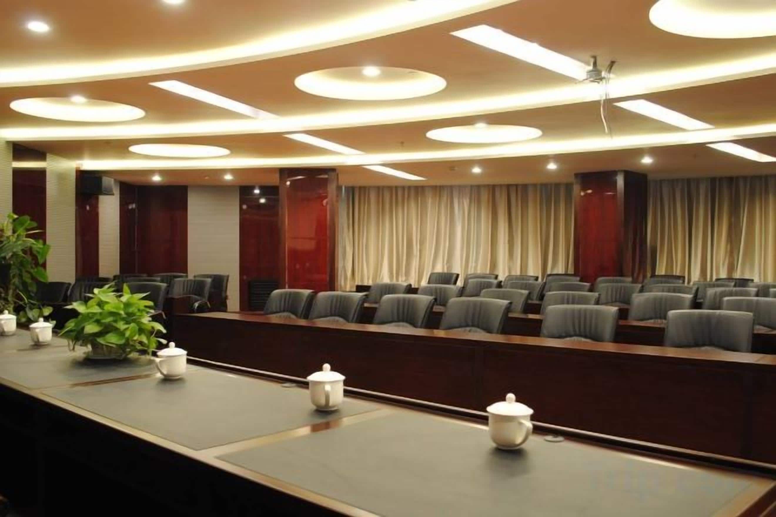 A conference room with a long table, multiple chairs, and a stage area.