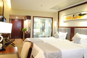 A hotel room with two beds, a desk, a chair, a mirror, and a painting on the wall.