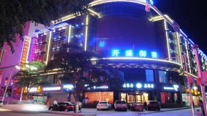 Un edificio de varios pisos con señalización iluminada, incluyendo un cartel llamativo para un restaurante y un hotel.