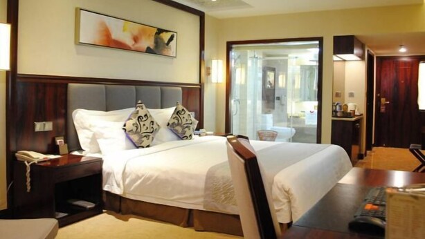 Habitación de hotel con una cama grande, un escritorio, una silla, un teléfono y un cuadro en la pared.