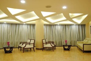 A lobby with a high ceiling, recessed lighting, a large column, and a seating area with chairs and a sofa. - Wanyuan Hotel (Baiyin)