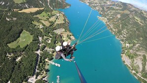 A person skydiving over a lake with a mountainous landscape in the background.