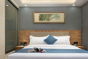 Una habitación de hotel con una cama grande, una obra de arte enmarcada sobre la cama y un cabecero de madera.