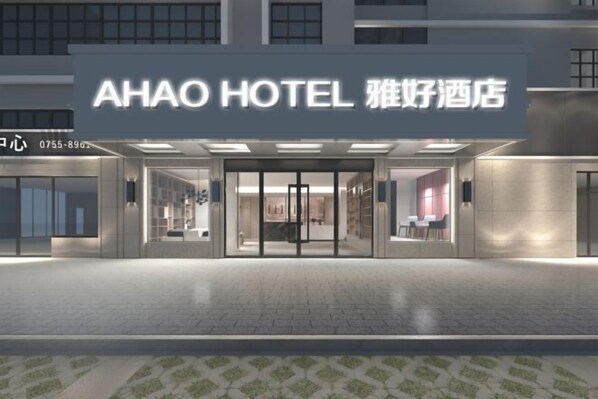 Una entrada de hotel moderna con fachada de vidrio, una zona de recepción y un número de teléfono visible.