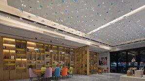 Un intérieur moderne avec un espace salon central, des étagères et un plafond orné de décorations suspendues.