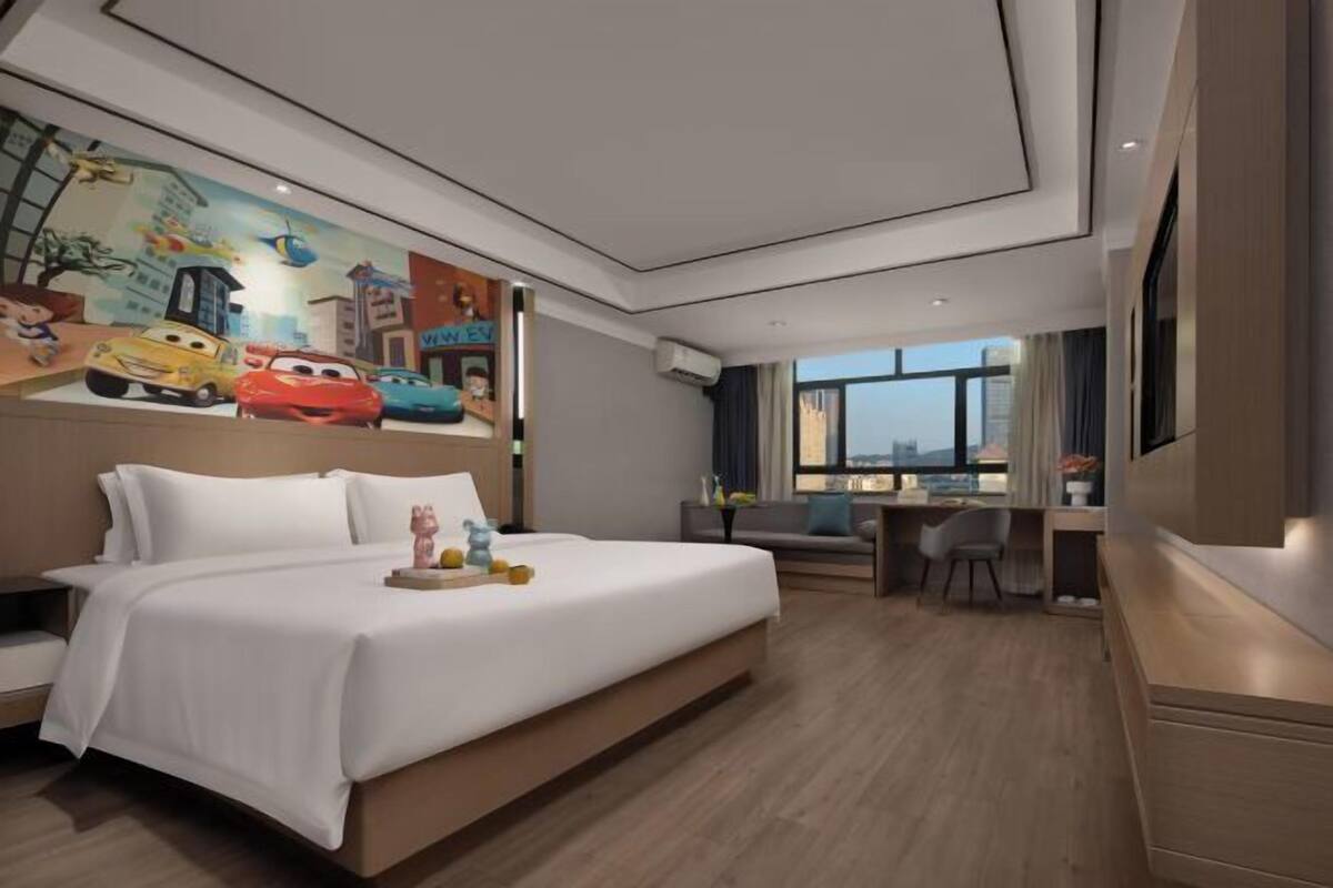 Una habitación de hotel moderna con una cama grande, un escritorio y vistas a la ciudad.
