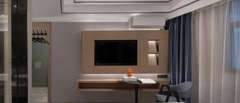 A modern hotel room with a large bed, a desk with a chair, a flat-screen TV, and a window with sheer curtains.