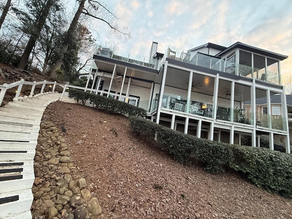 A modern multi-story building with a glass facade, a wooden deck, and a stone retaining wall.