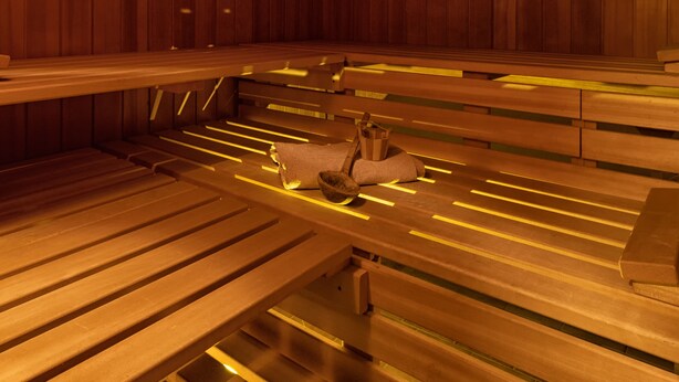 A sauna with wooden benches and benches, and a small wooden structure in the center. - Exclusive (top floor) new-build vacation apartment with distant views (Konstanz)