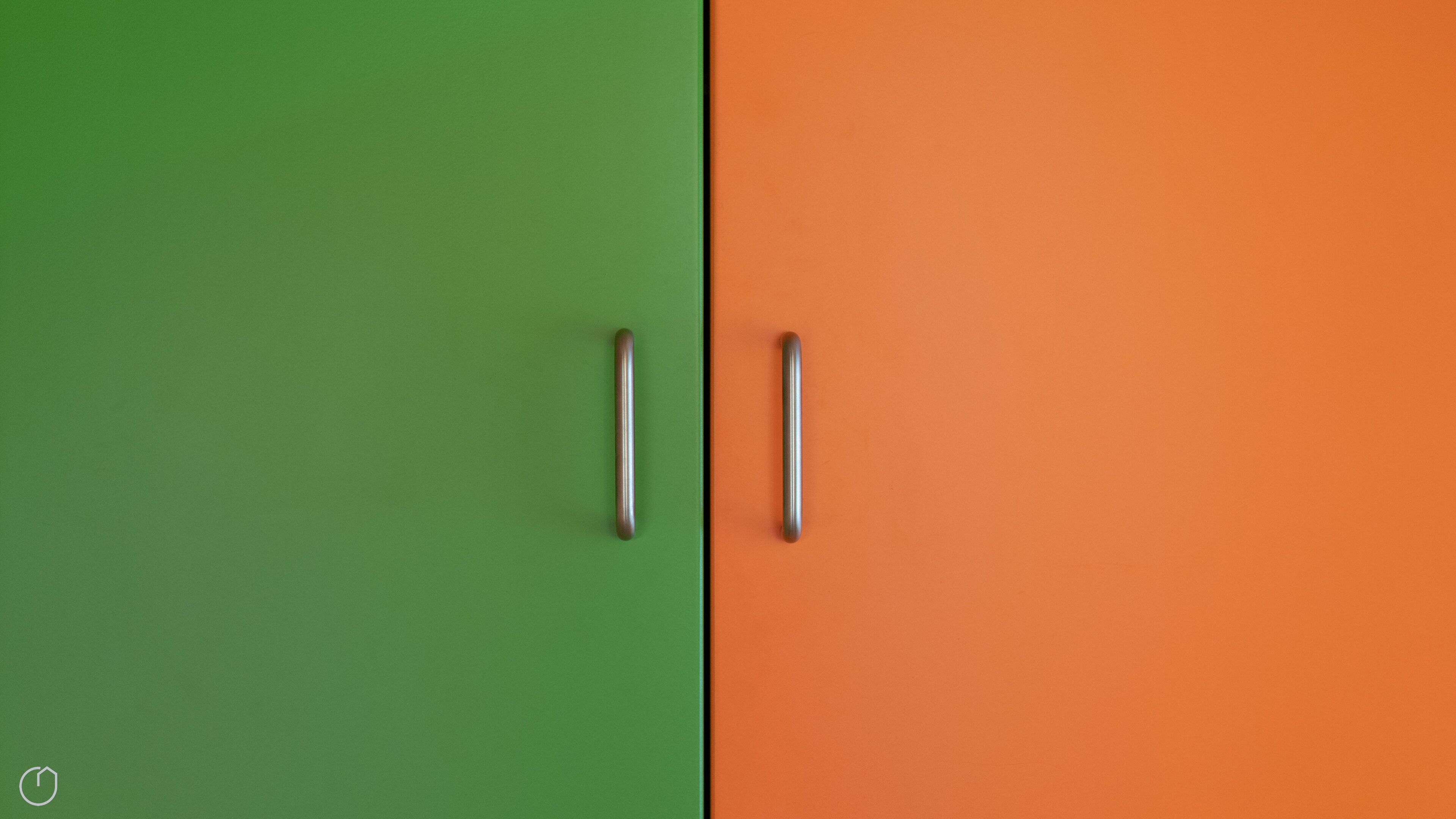 Um armário de duas portas com puxadores metálicos, uma porta verde e outra laranja.