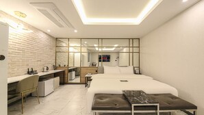 A modern hotel room with a bed, a desk, a chair, a small kitchenette, and a large mirror. - Hotel 24st Urban Brown Seosan Lake Park (Seosan)