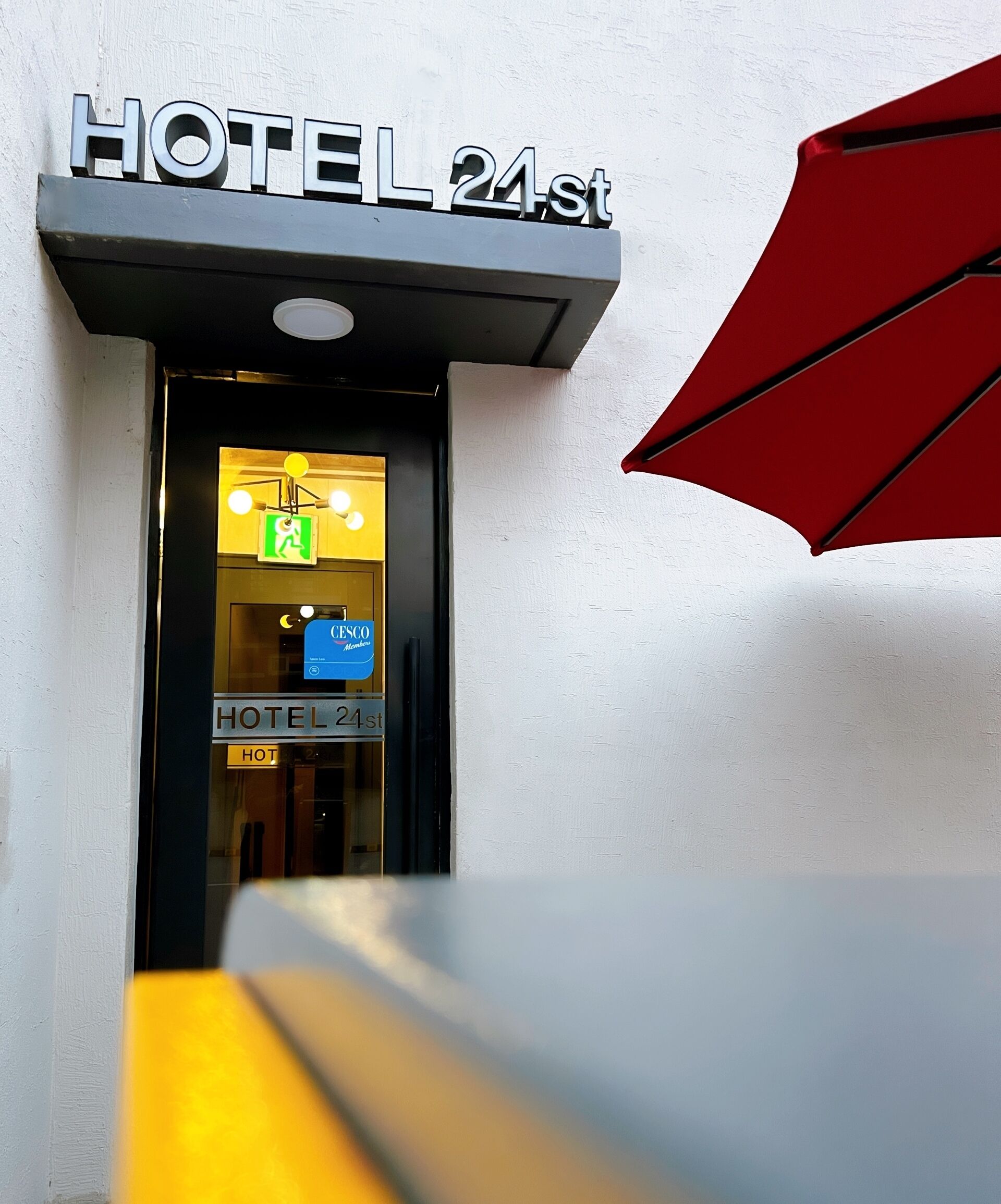 Entrada de hotel con un letrero que dice "HOTEL 24st" y un letrero de salida de emergencia visible.