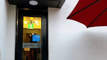 A hotel entrance with a sign reading "HOTEL 24st" and a visible emergency exit sign.