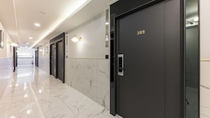A modern hallway with marble flooring, a black elevator with the number 309, and wall-mounted lighting. - Hotel 24st Urban Brown Seosan Lake Park (Seosan)