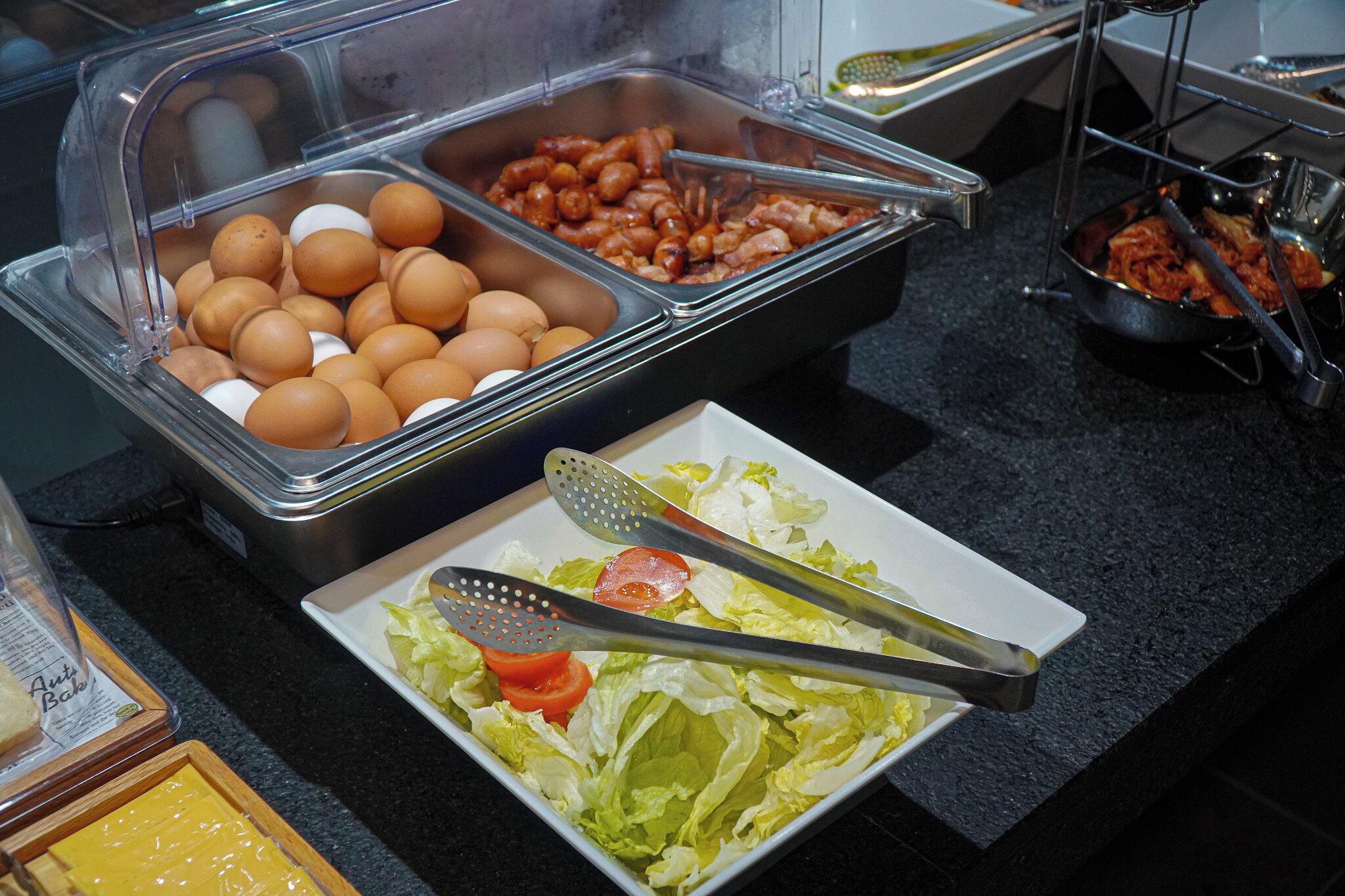 A buffet with various food items including eggs, beans, and a salad with lettuce and tomatoes.