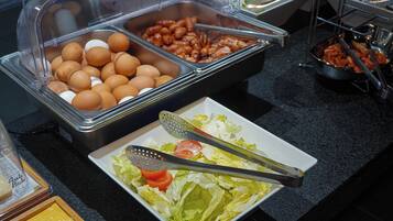 A buffet with various food items including eggs, beans, and a salad with lettuce and tomatoes.