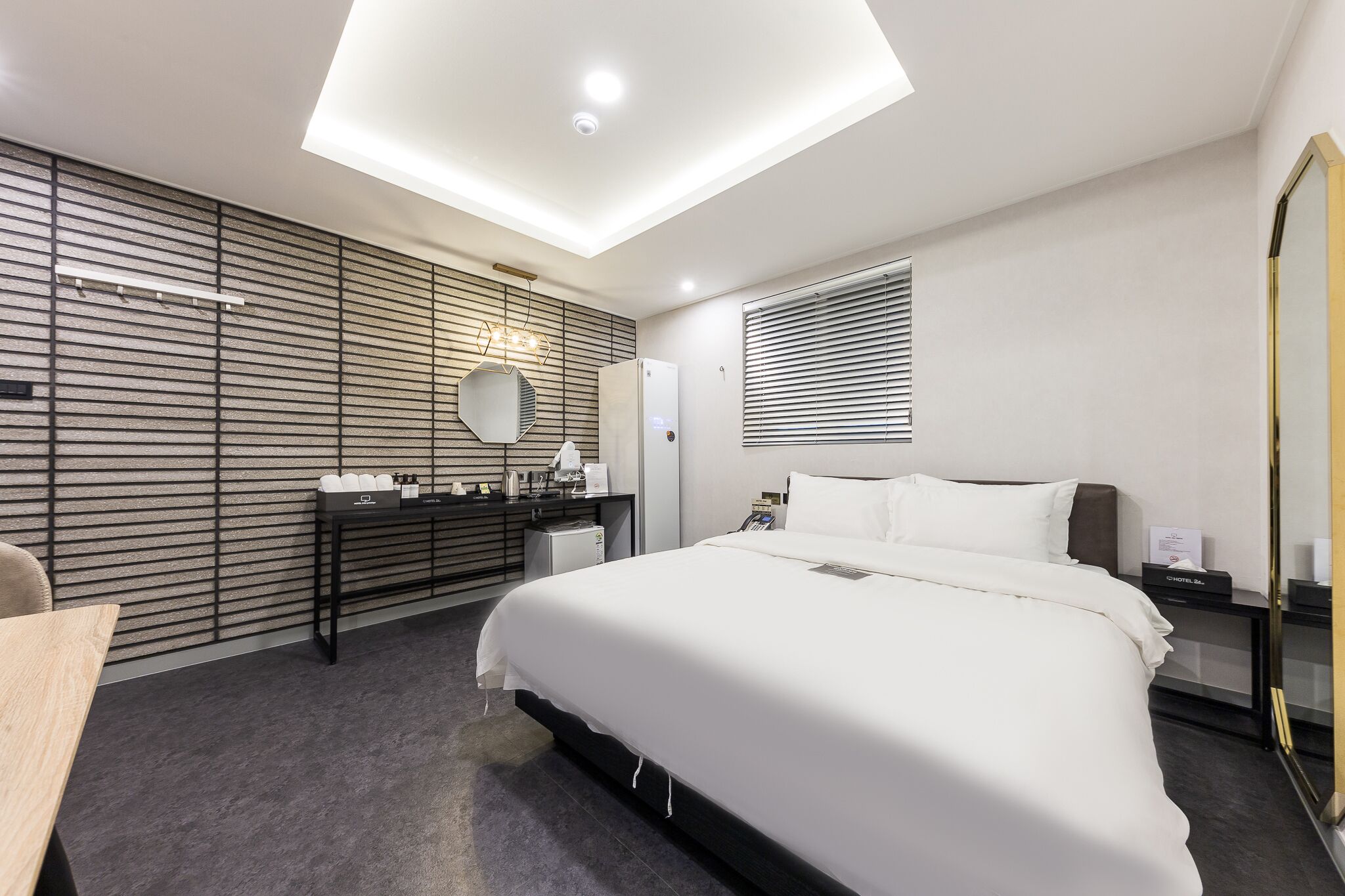 Une chambre d’hôtel moderne dotée d’un grand lit, d’un bureau, d’un miroir et d’une armoire intégrée.