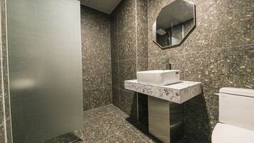 Un baño moderno con lavamanos de mármol, un espejo y un inodoro.