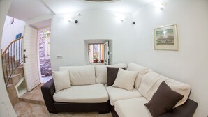 A living room with a sectional sofa, a staircase, and a small window. - Old Town Apartment Dan (Budva)