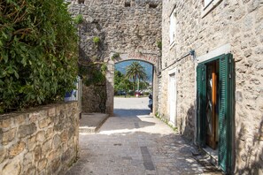 A narrow stone pathway leading to a stone building with a doorway and a sign above it.