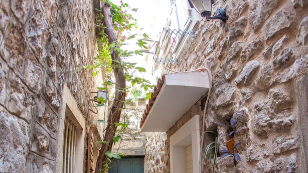 A narrow stone alleyway with a wooden door and a small bench. - Old Town Apartment Dan (Budva)