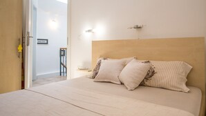 A bedroom with a large bed, two pillows, a nightstand, and a wall-mounted light fixture. - Old Town Apartment Dan (Budva)