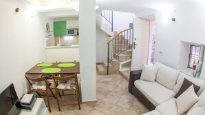 A modern apartment with a dining area, a sofa, and a staircase leading to an upper floor. - Old Town Apartment Dan (Budva)