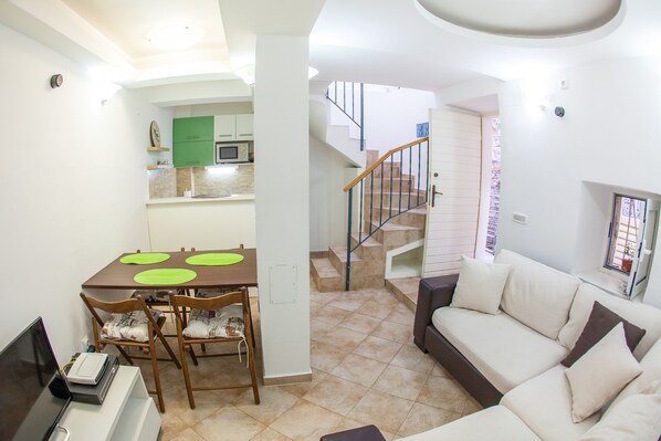 A modern apartment with a dining area, a sofa, and a staircase leading to an upper floor.