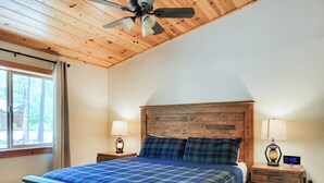 A bedroom with a wooden ceiling, a bed with a plaid bedspread, two bedside tables with lamps, and a digital clock. - White Oak Retreat in Pinetop Country Club w/Firepit/Grill/Horseshoes! (Pinetop)
