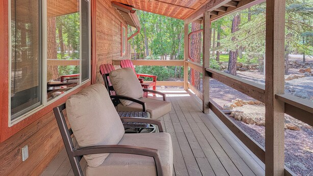 A covered porch with wooden flooring and two cushioned chairs. - White Oak Retreat in Pinetop Country Club w/Firepit/Grill/Horseshoes! (Pinetop)