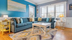 A living room with a blue sofa, a white coffee table, and a patterned rug.
