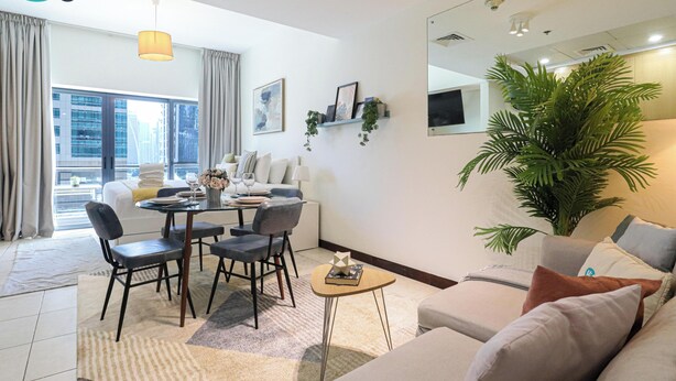 Uma sala de estar moderna com área de jantar, janelas grandes e uma planta grande.