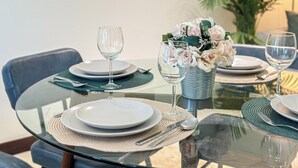 Mesa posta com pratos, talheres e um vaso de flores.