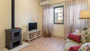 A living room with a fireplace, a television, a sofa, and a window with curtains. - Gaya Avenue 102 - Flat w/ Balcony (Vila Nova de Gaia)