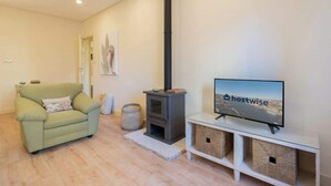 A living room with a sofa, a television, a fireplace, and a wall-mounted TV. - Gaya Avenue 102 - Flat w/ Balcony (Vila Nova de Gaia)