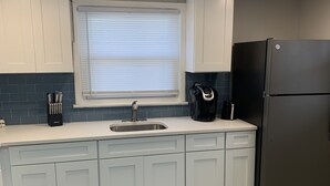 A kitchen with white cabinets, a black refrigerator, a window with blinds, and a sink. - Two bedroom private home less than 1 block away from the beach (Seaside Park)