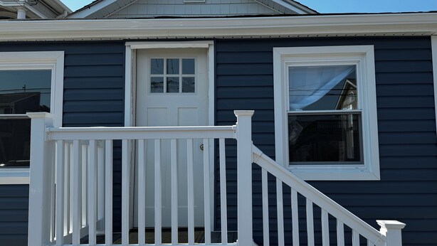 A two-story house with a white front door, a small window, and a white front porch with a railing. - Two bedroom private home less than 1 block away from the beach (Seaside Park)