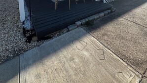 A single-story house with a dark gray exterior and white trim. It features a front porch with a small table and two chairs, a white picket fence, and a number "37" on the front door. - Two bedroom private home less than 1 block away from the beach (Seaside Park)