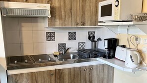 Une cuisine avec des meubles de rangement en bois, un four à micro-ondes, une machine à café et un grille-pain.