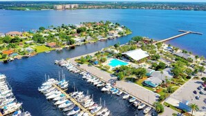 An aerial view of a marina with numerous boats docked, a swimming pool, and residential buildings.