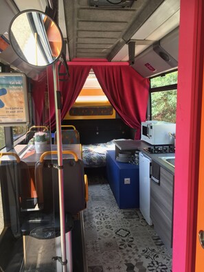 Un espace de vie compact comprenant un lit, une kitchenette et un coin salon.